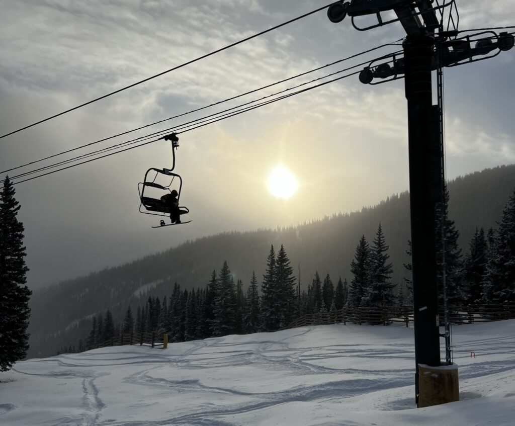 snowboarder on a chairlift with fresh snow
